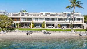 Un edificio moderno de dos pisos con balcón, mobiliario exterior y vista al agua.