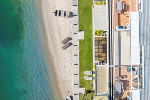 An aerial view of a beachside property with a swimming pool, lounge chairs, and a building with a tiled roof. - Riverfront with Beach (Noosaville)