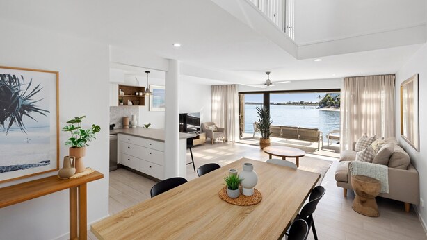 Un interior moderno con comedor, cocina y sala de estar con vista al agua.