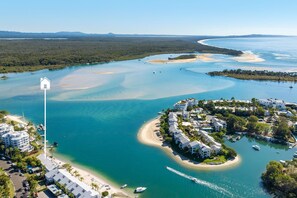 An aerial view of a coastal resort with beachfront properties, clear waters, and a marina.