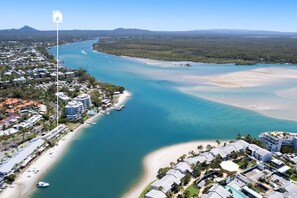An aerial view of a coastal area with a marina, beachfront properties, and a dense residential area.
