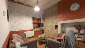 A cozy living room with a stone wall, a fireplace, a clock, and a comfortable sofa.