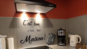 A kitchen with a stainless steel range hood, a coffee maker, a kettle, and a toaster.