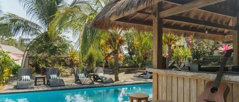 A poolside area with lounge chairs, a bar, and a guitar.