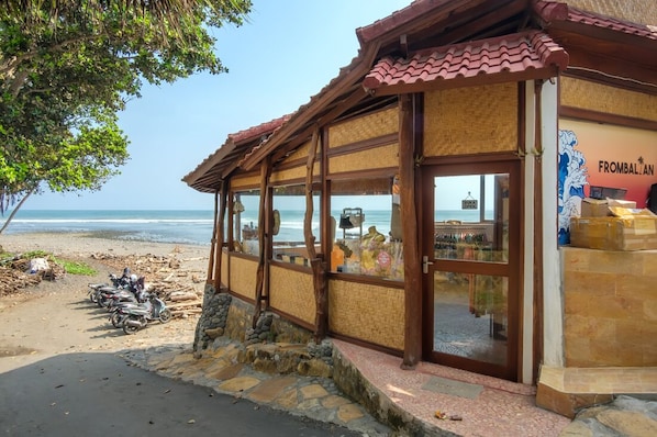 Un edificio frente a la playa con techo de tejas y grandes ventanales.
