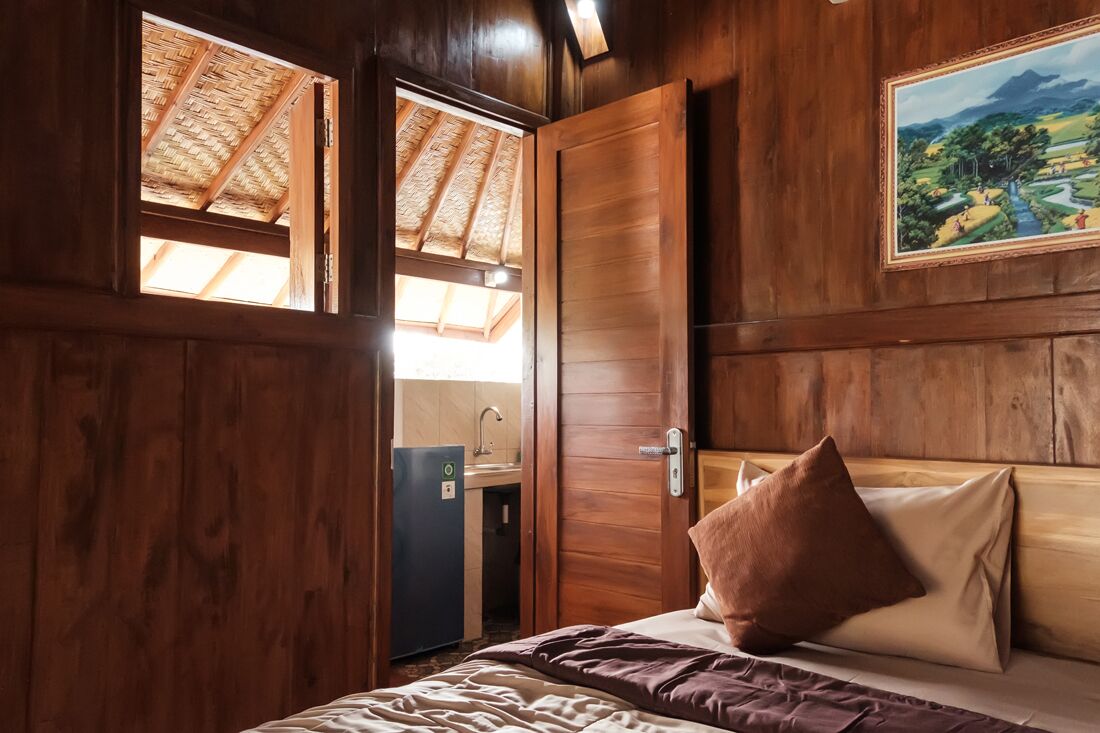 Una habitación de madera con una cama, una puerta y una ventana.