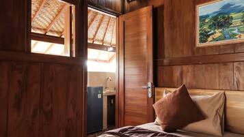 Una habitación de madera con una cama, una puerta y una ventana.
