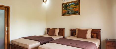 A room with two beds, wooden headboards, a painting on the wall, and an air conditioning unit.