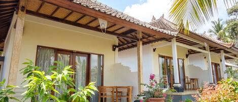 A traditional-style building with a tiled roof, wooden pillars, and a covered patio area with a table and chairs.