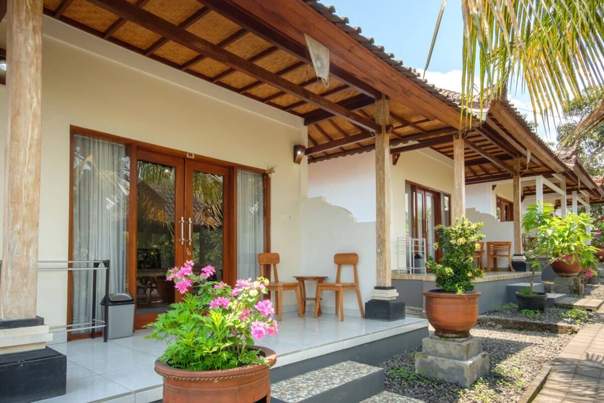 A covered outdoor area with wooden pillars, a tiled floor, and potted plants.