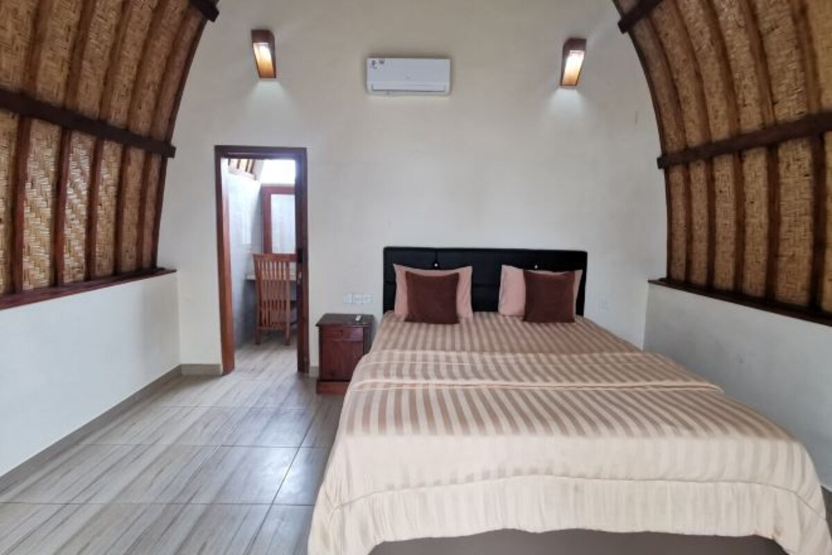 A bedroom with a bed, a nightstand, and a wooden-framed window.