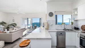 A modern kitchen with a central island, white cabinetry, and a dishwasher. - Bayview Towers 10 With Harbour Views (Nelson Bay)