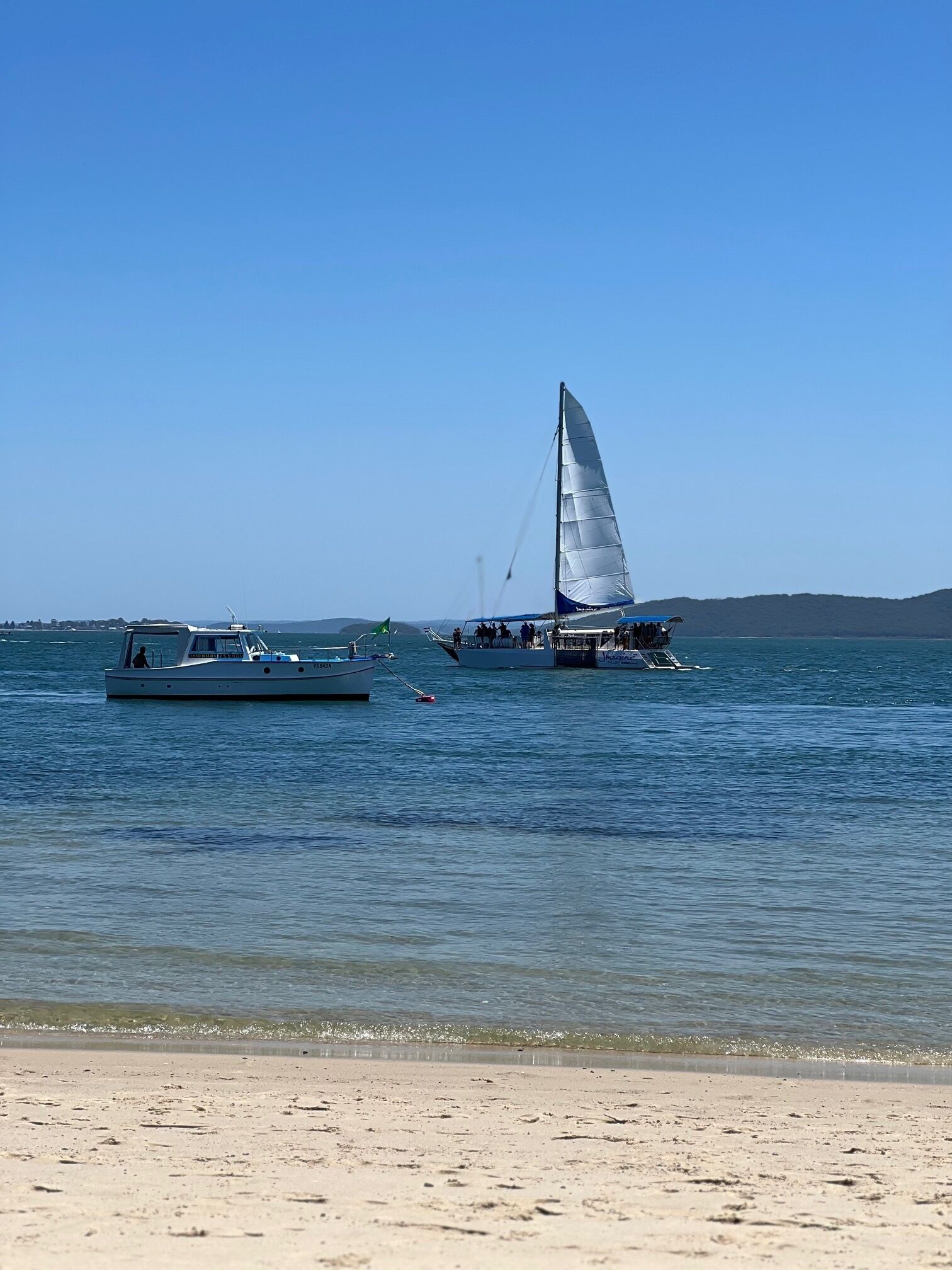 Une plage avec des bateaux sur l’eau et un rivage sablonneux.