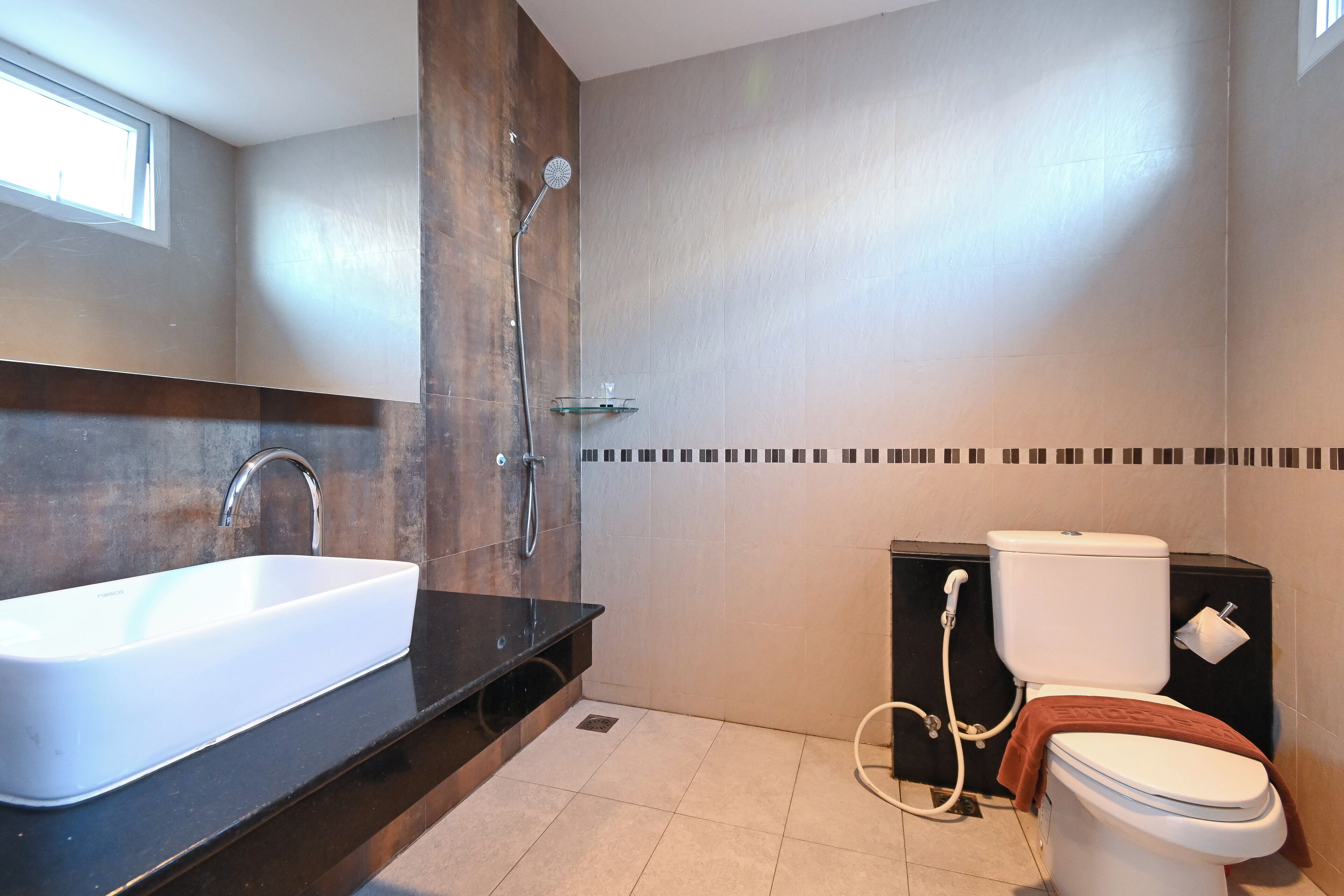 A modern bathroom with a large white sink, a shower, and a toilet.