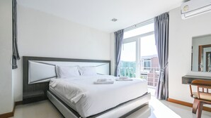 Ein modernes Hotelzimmer mit einem großen Bett, einem Schreibtisch und Blick auf die Stadt.