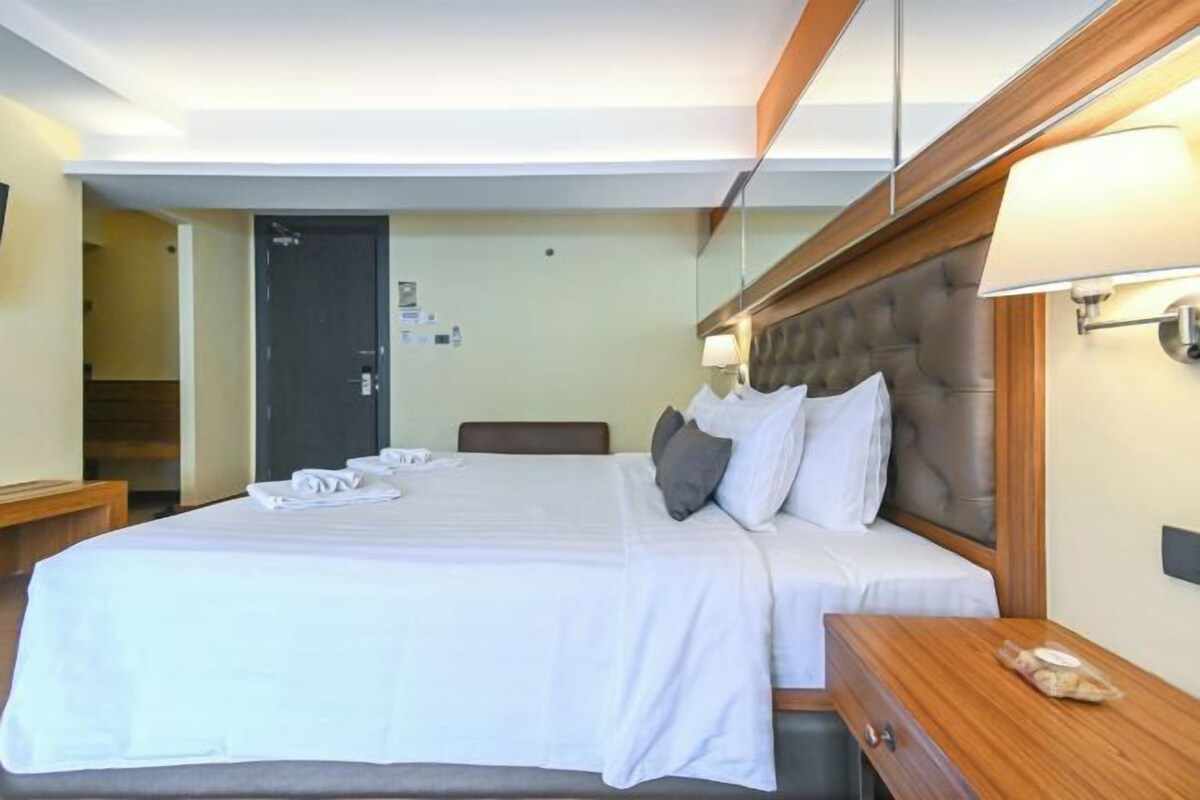 A hotel room with a large bed, a wooden headboard, a bedside table, and a nightstand.