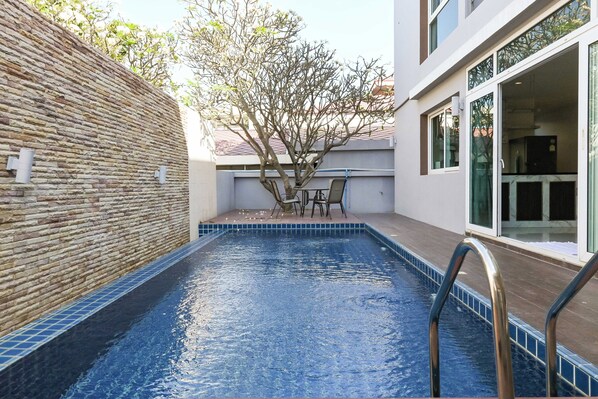 A swimming pool with a stone wall and a tree in the background. - Golden Sea Pool Villa Hua Hin (Cha-am)
