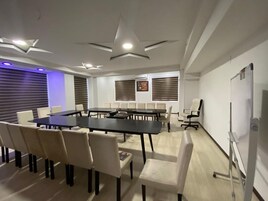 Un salón de conferencias con una mesa grande, sillas y una pizarra.