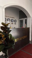 Un mostrador de recepción con un cartel que dice 'RECEPTION' y relojes encima.