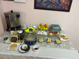 Una mesa con distintos alimentos, una cafetera y un cuadro en la pared.