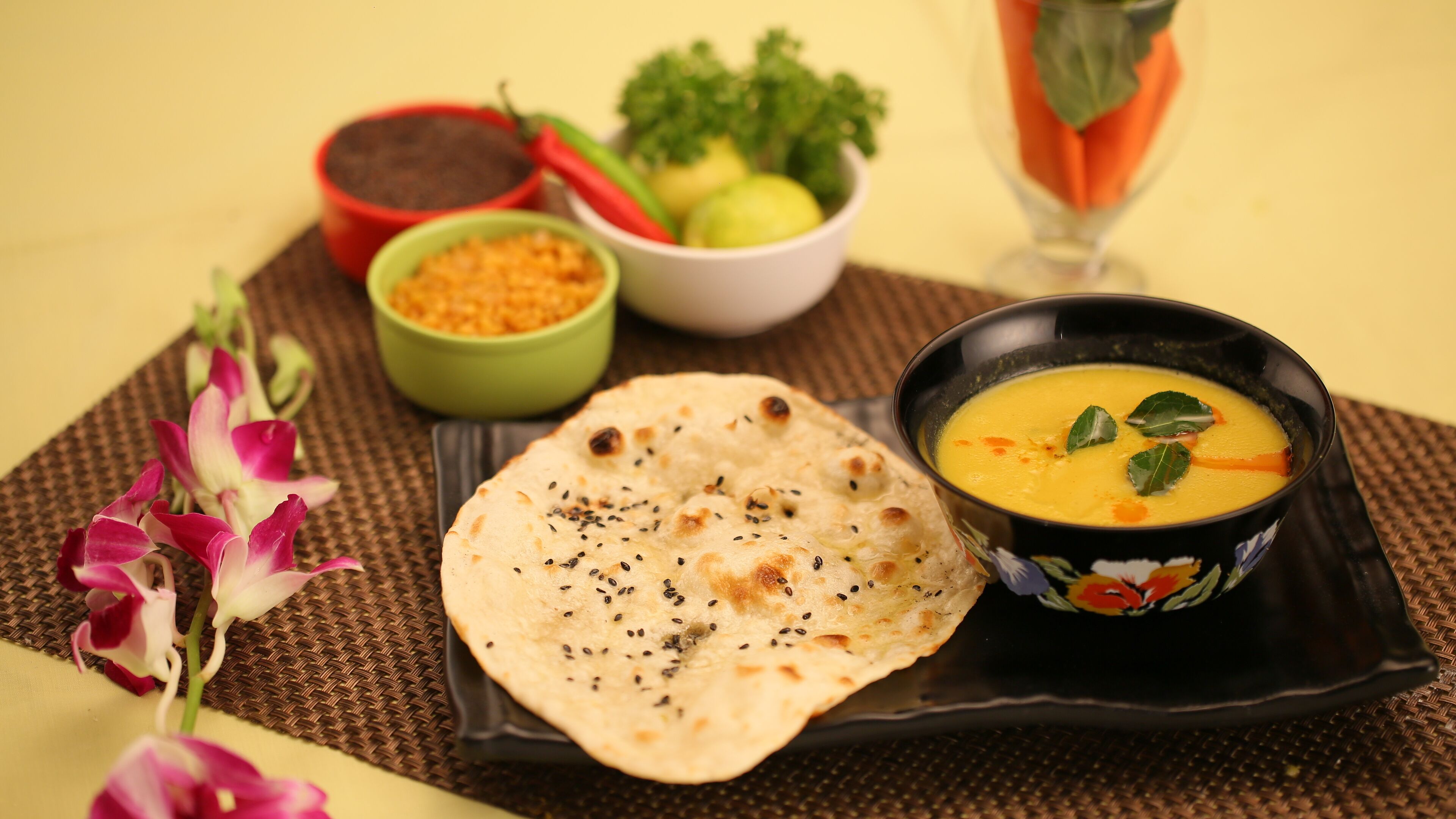 A meal with naan bread, a bowl of soup, and a plate of vegetables.