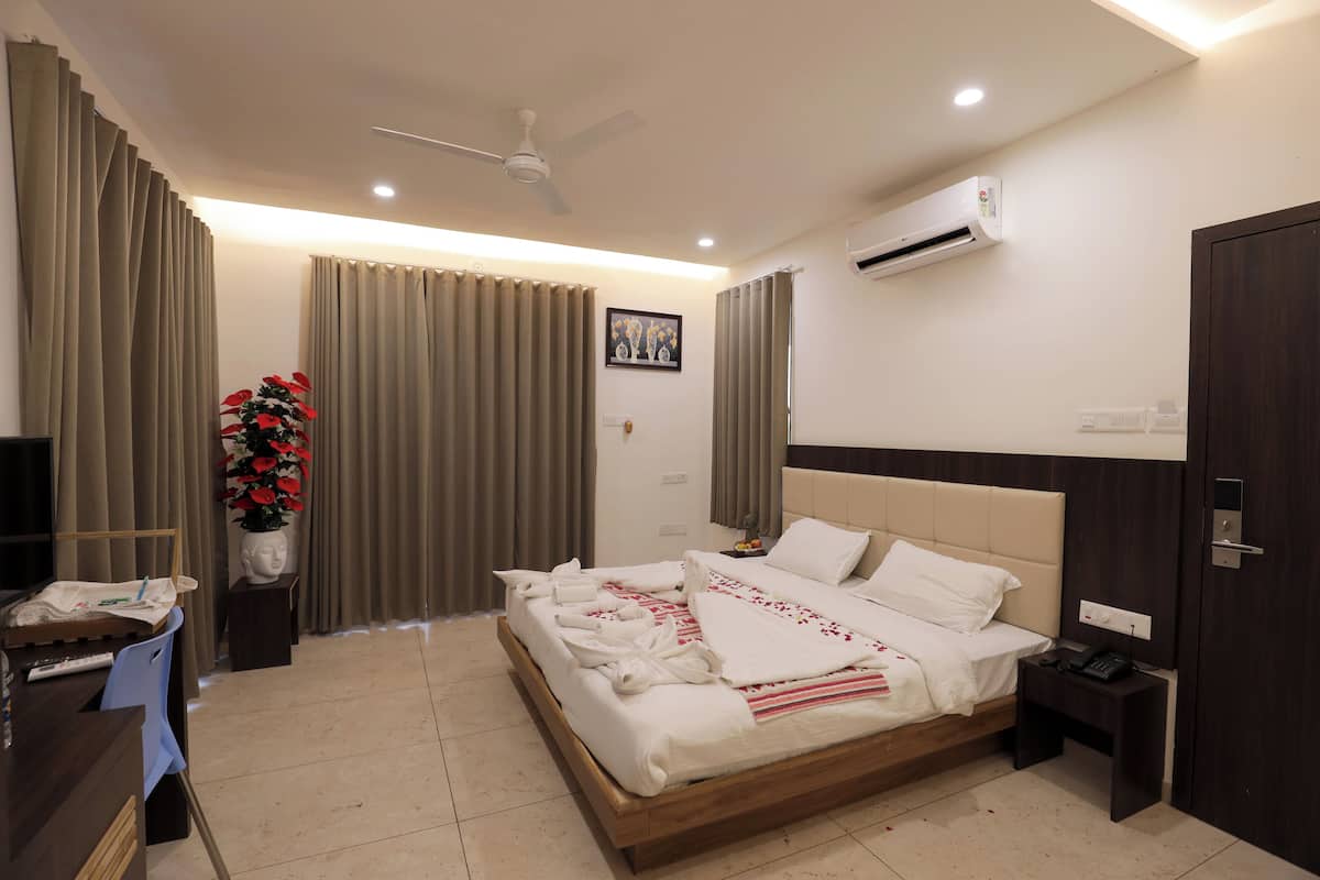 A hotel room with a bed, bedside table, nightstand, and a desk with a chair.