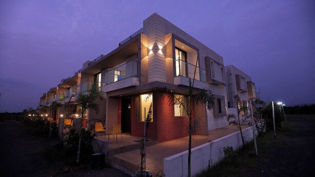 Un moderno edificio residencial de varios pisos con balcones, ventanas amplias y una entrada bien iluminada.