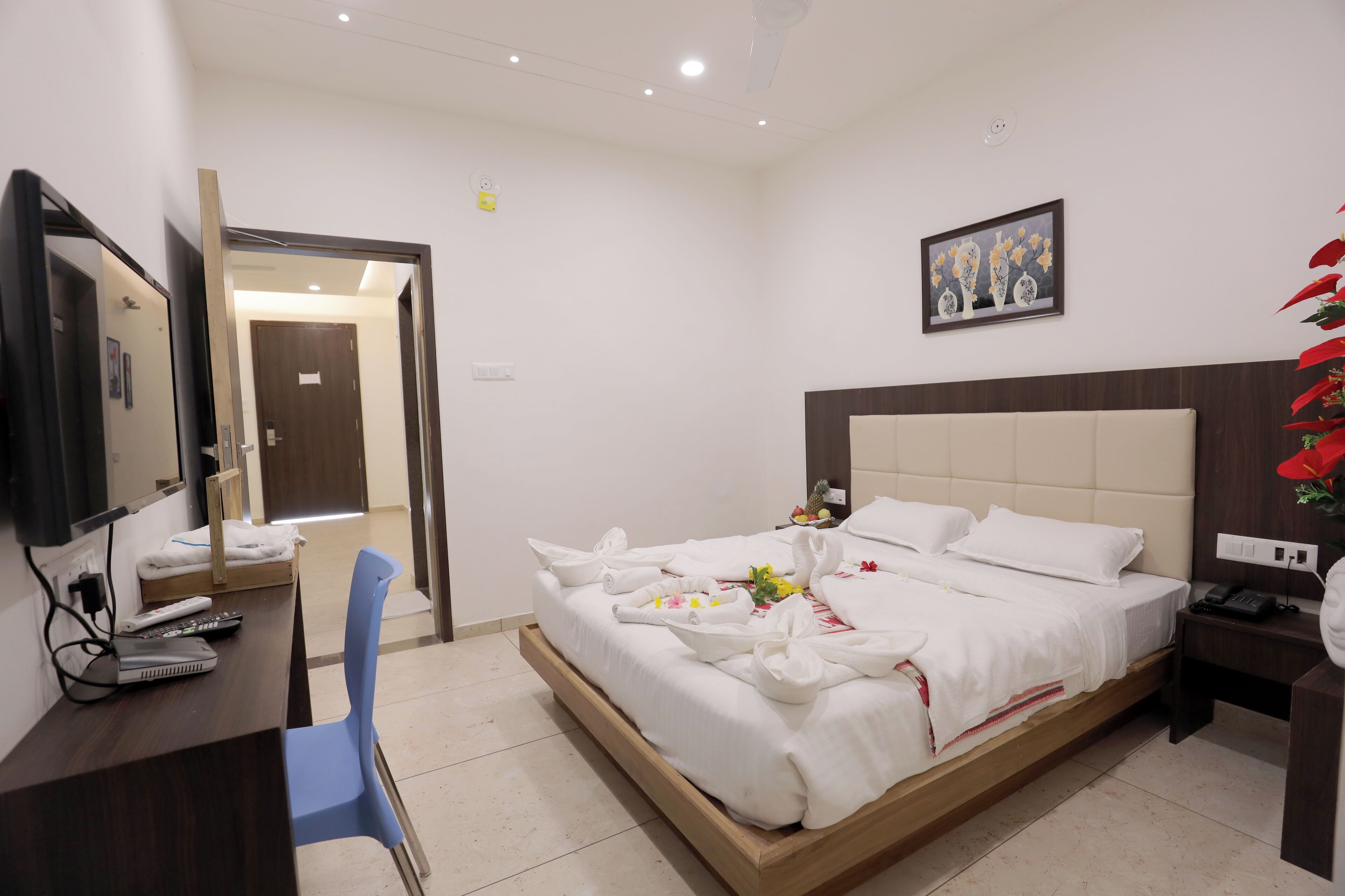 Una habitación de hotel con cama, escritorio, silla, televisor y un cuadro en la pared.