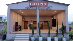 A building labeled "Leena Resort" with a reception desk, seating area, and potted plants.