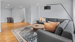 En moderne stue med en grå sofa, et rundt sofabord og et tæppe med et mønster.