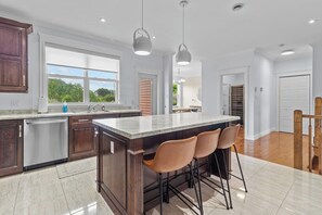 Una cocina moderna con una isla central, taburetes de bar e iluminación colgante.