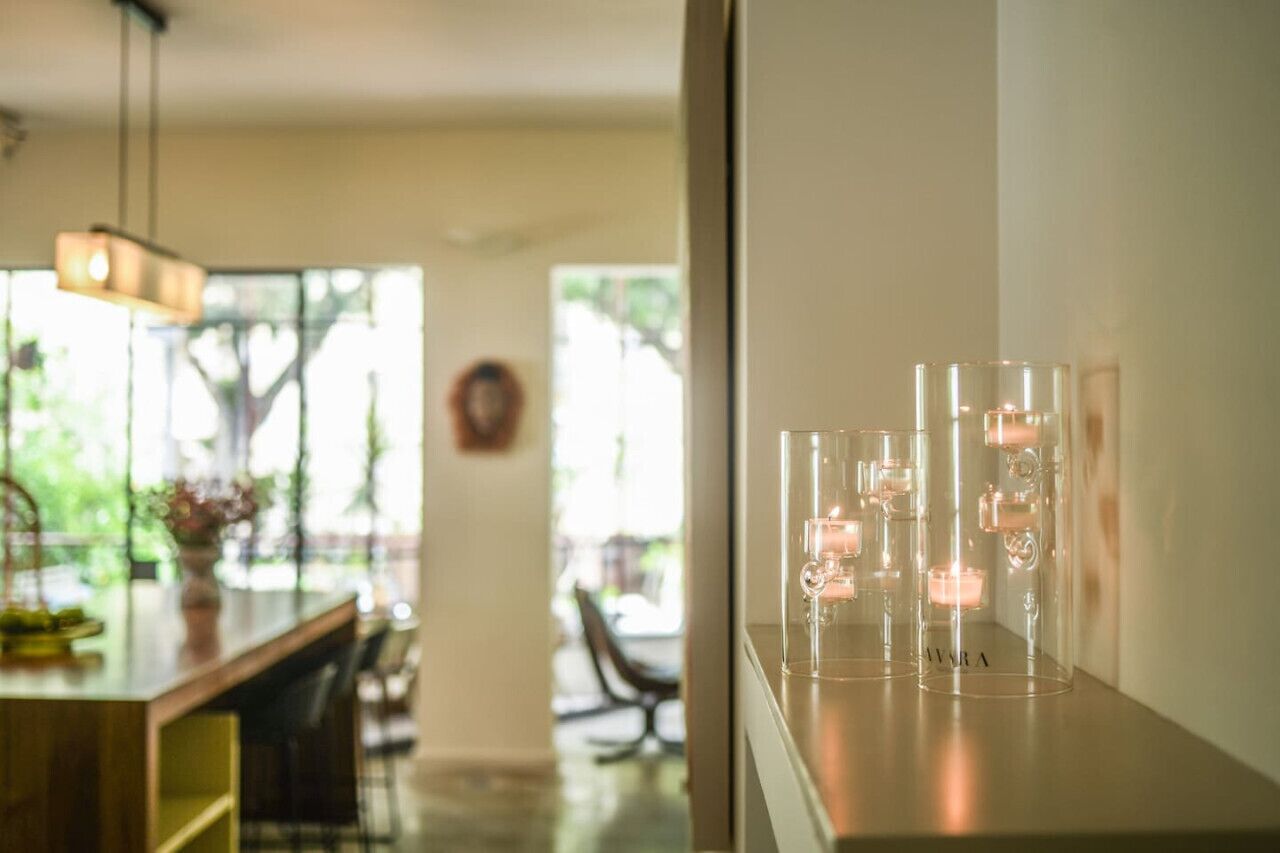 Un intérieur moderne comprenant un coin repas, un bar et une étagère avec des récipients en verre transparent contenant des bougies.