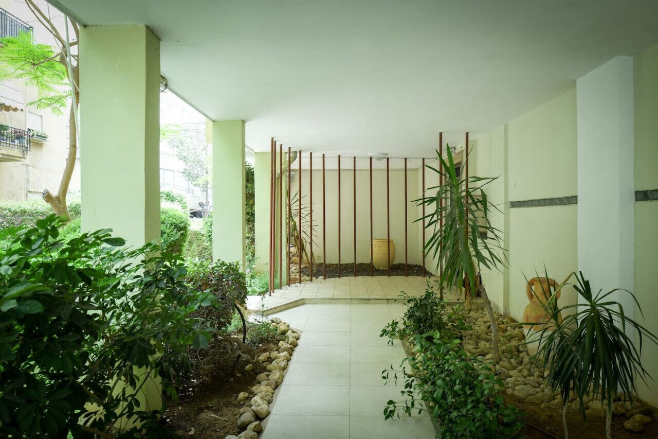 A serene indoor garden with a tiled floor, a bamboo fence, and various potted plants.