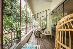 Ein Balkon mit Tisch, Stühlen und Blumentöpfen.