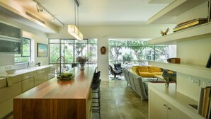 A modern kitchen with a wooden island, large windows, and a seating area with a yellow sofa. - Spacious & Green 3BR Apt w Balcony (Tel Aviv)