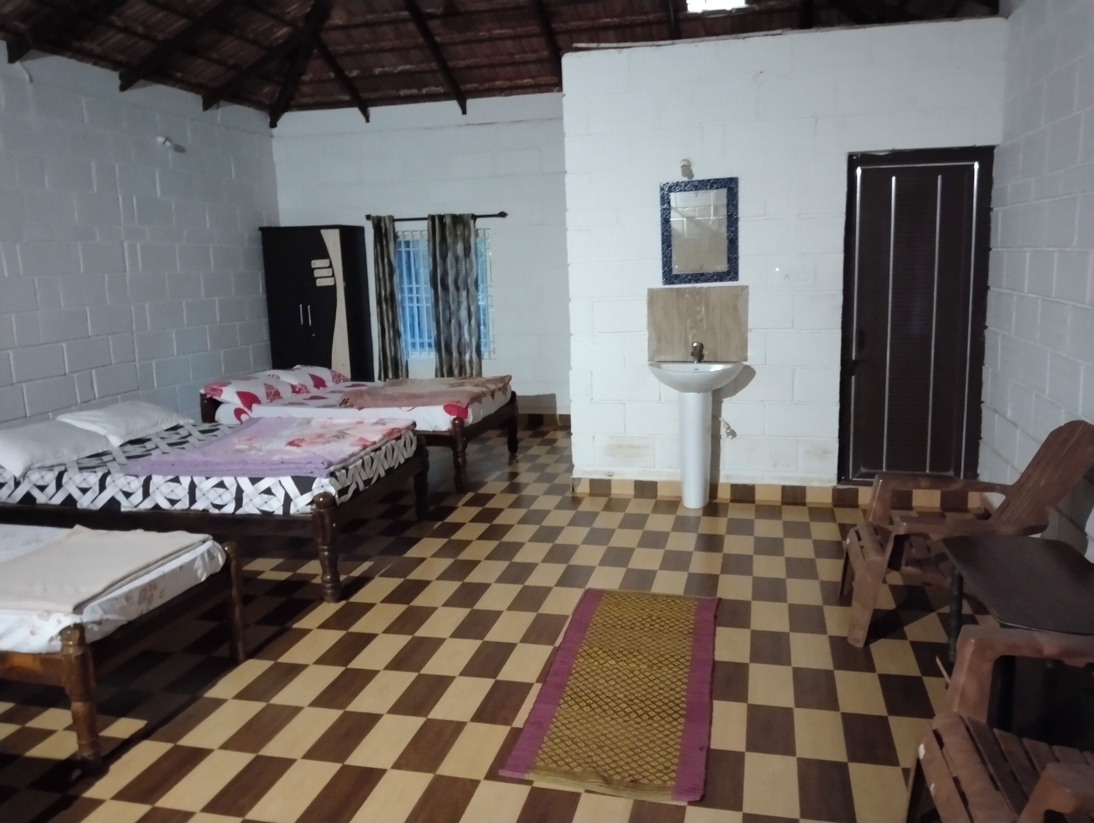 Une chambre avec deux lits, un lavabo, un miroir et un sol à carreaux.