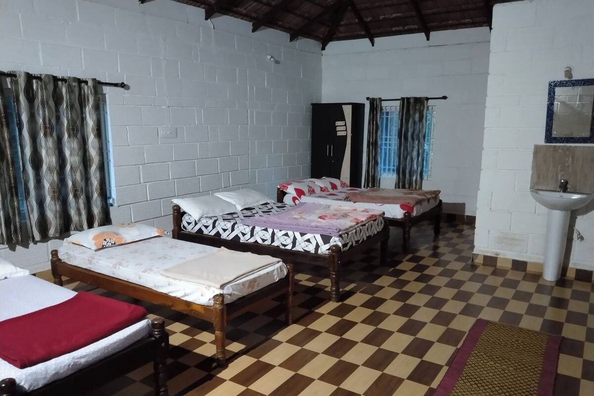 A room with three wooden beds, a checkered floor, a white sink, and a window with curtains.