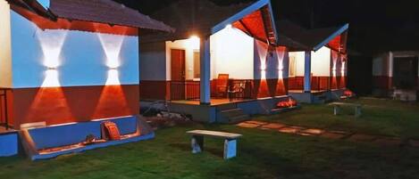 A series of connected buildings with outdoor seating areas and a well-lit pathway.