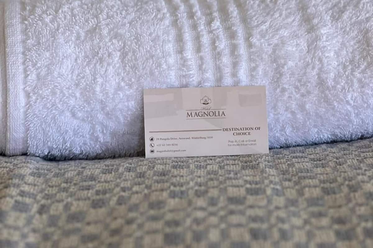 Um conjunto de artigos de higiene pessoal bem organizado e um cartão de boas-vindas sobre um sofá com textura.