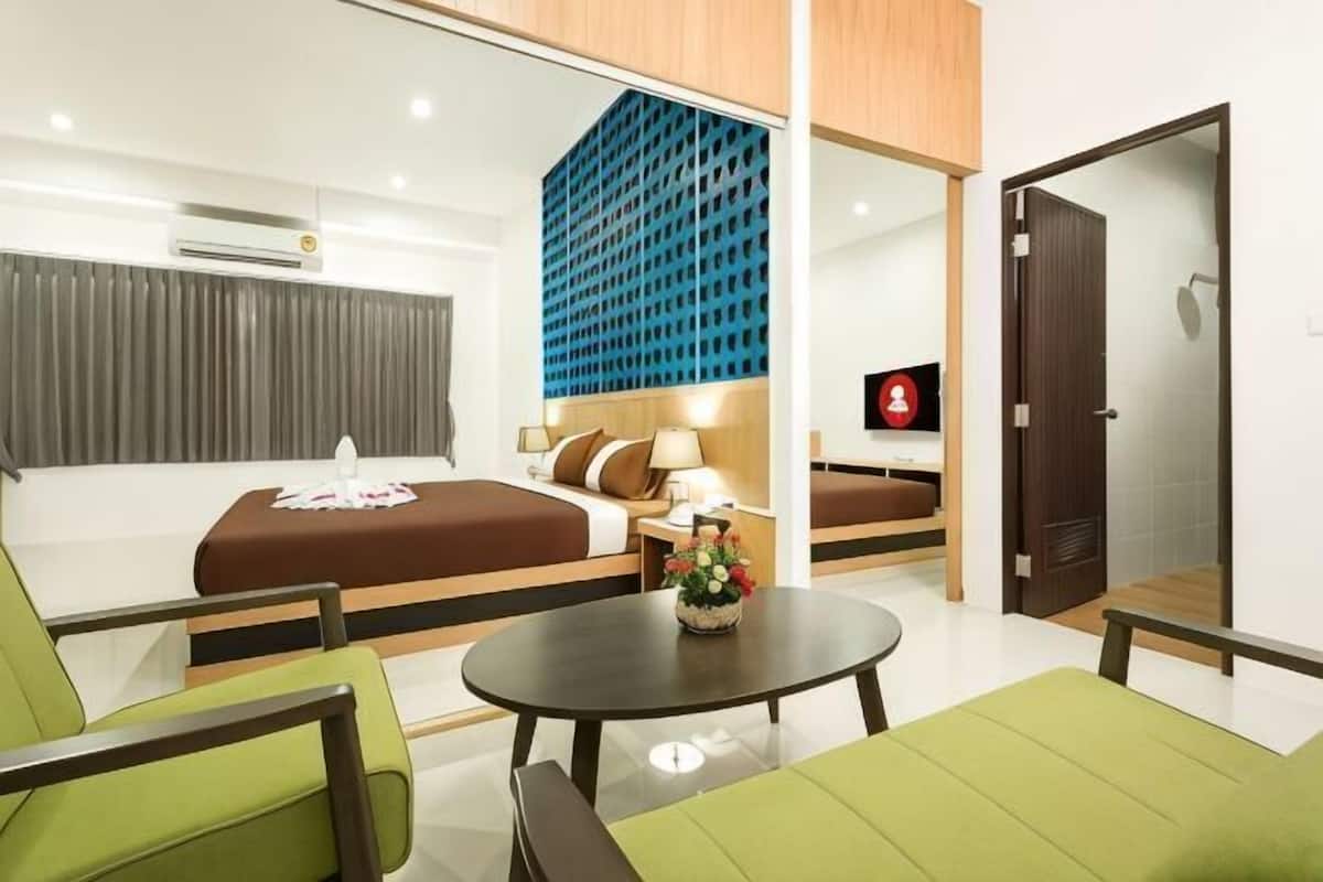 A modern hotel room with a bed, a sofa, a small table, and a TV.