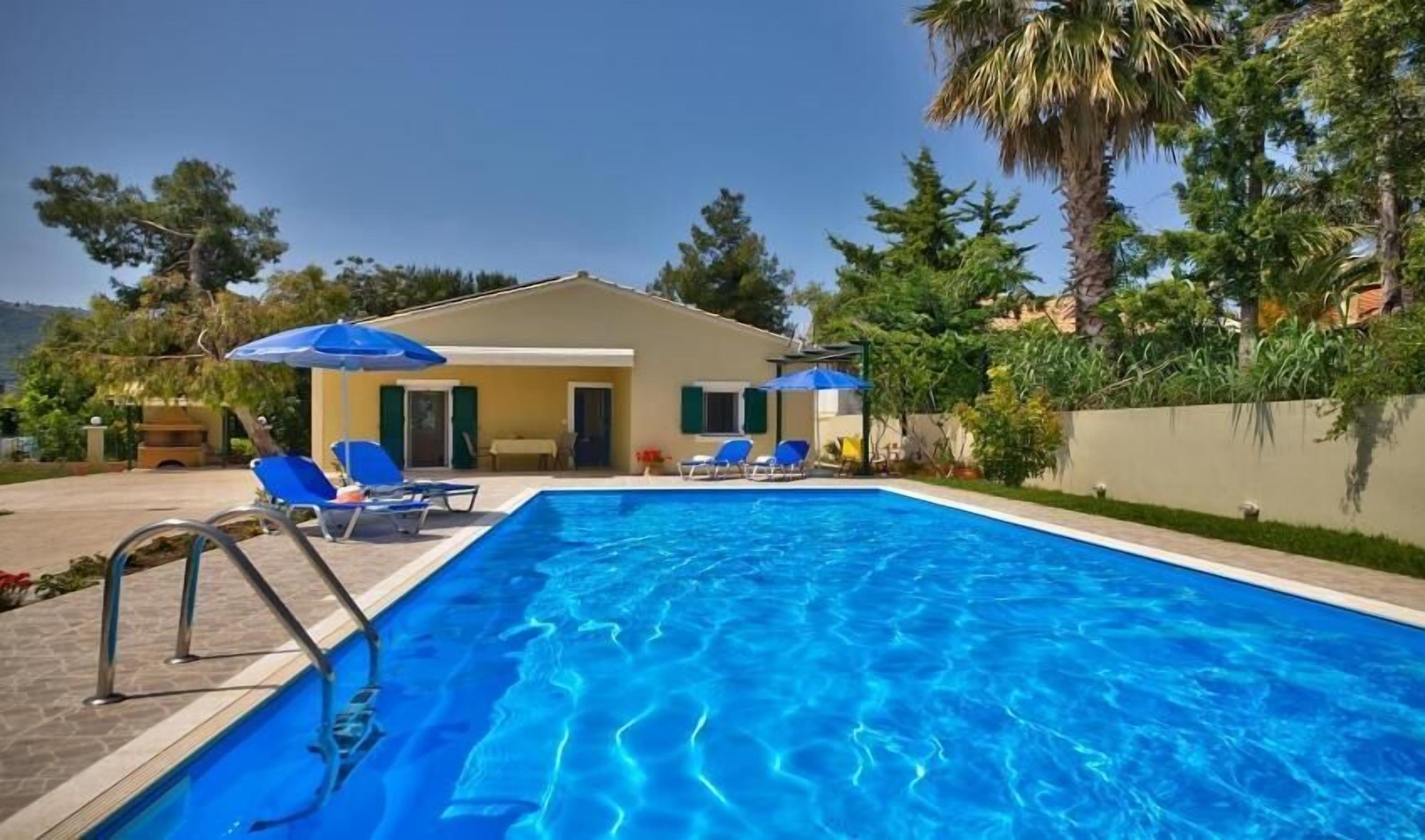 Ein Swimmingpool mit blauem Wasser, umgeben von Liegestühlen und Sonnenschirmen.