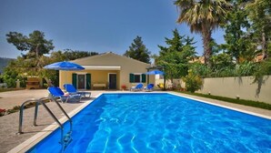 A swimming pool with blue water, surrounded by lounge chairs and umbrellas. - Nyktelia Holiday Villa (Lefkada)