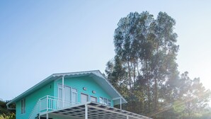 A turquoise two-story building with a covered porch and a staircase. - Blossom Inn (Coonoor)