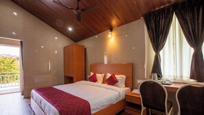 A bedroom with a bed, a desk, and a chair. - Blossom Inn (Coonoor)