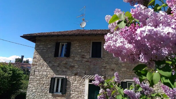 Ein Gebäude aus Stein mit Satellitenschüssel, Fensterläden und einem Fenster.