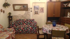 Un salon chaleureux avec un canapé à motifs floraux, une table à manger avec des chaises et un buffet.