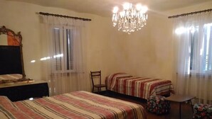 Ein Zimmer mit zwei Betten, einer Deckenleuchte, einem Tisch und einem Stuhl.