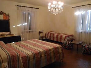 Une chambre avec deux lits, un lustre, une table et une chaise.