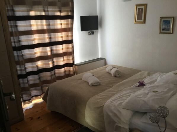 A bedroom with a bed, a TV mounted on the wall, and a window with curtains. - Lavender Hill Hvar (Stari Grad)