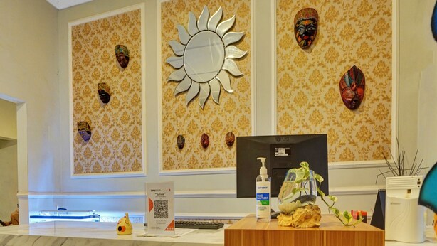 A reception desk with a mirror, a computer, and a hand sanitizer dispenser. - Hotel O Btc Guest House Syariah (Malang)